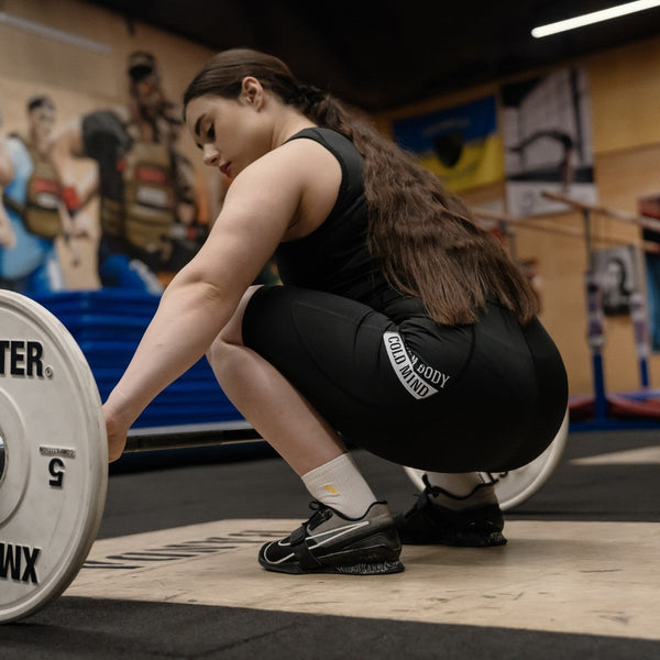 Person in WOMEN'S WEIGHTLIFTING COMPRESSION SINGLET S-4 performing a weightlifting exercise in a gym setting - Warm Body Cold Mind